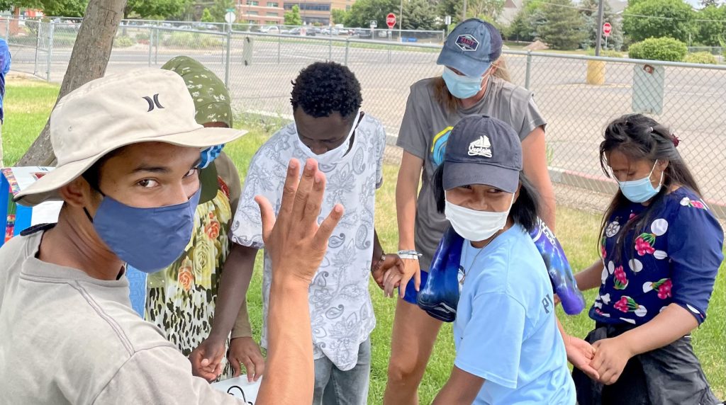 Students in masks standing in a circle holding hands. The activity is described in the text.