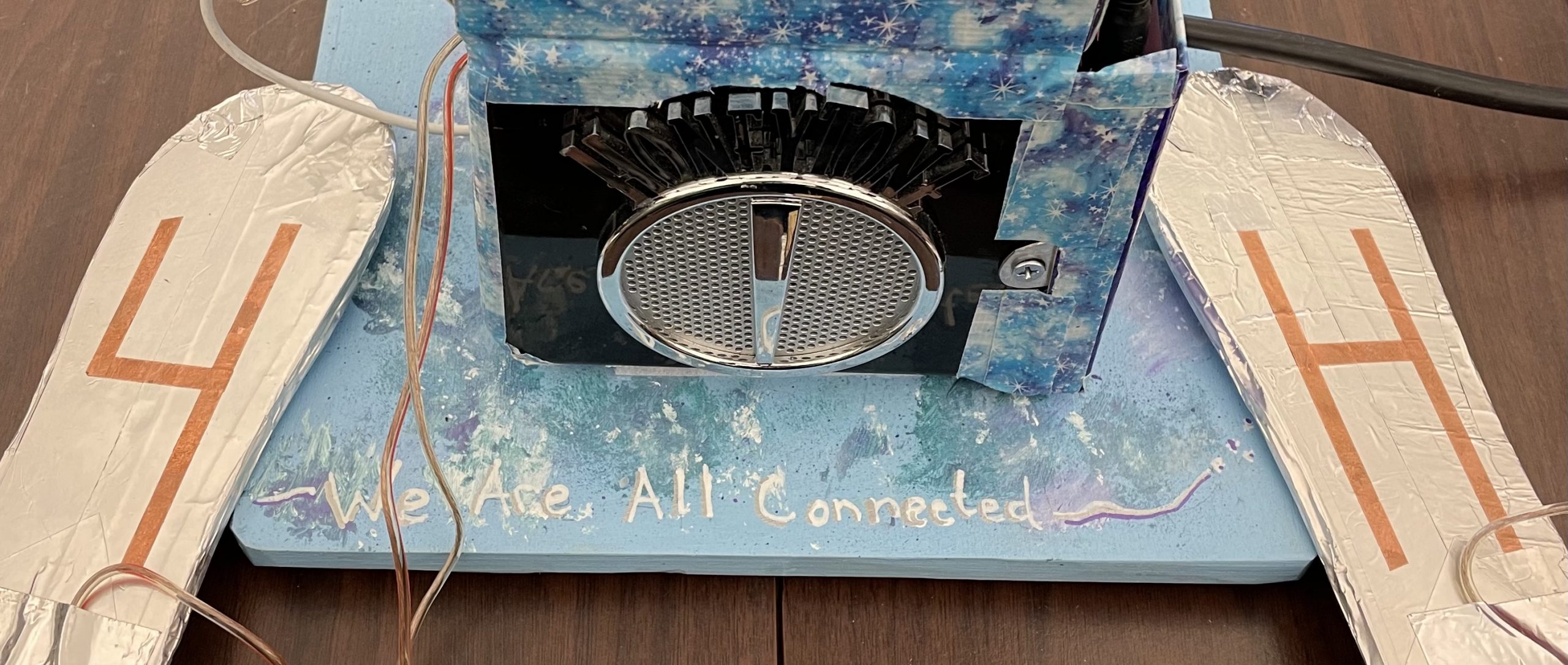 The is an image of an amplifier and MP3 player connected to paddles covered in aluminum tape. This is the We Are All Connected hands-on experiment.