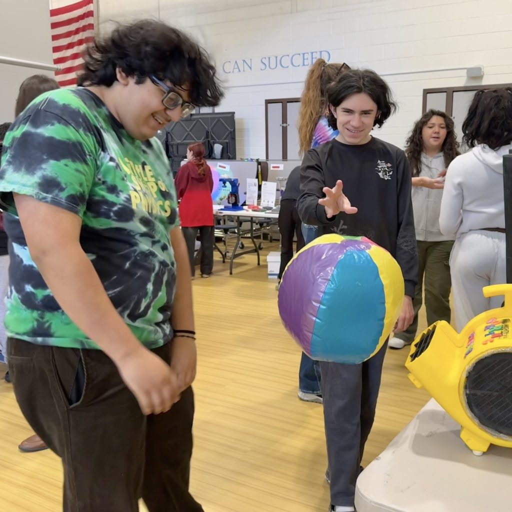 54828275247_f99a43b009_k Abram in tie dye watching as student holds hand near levitating beachball