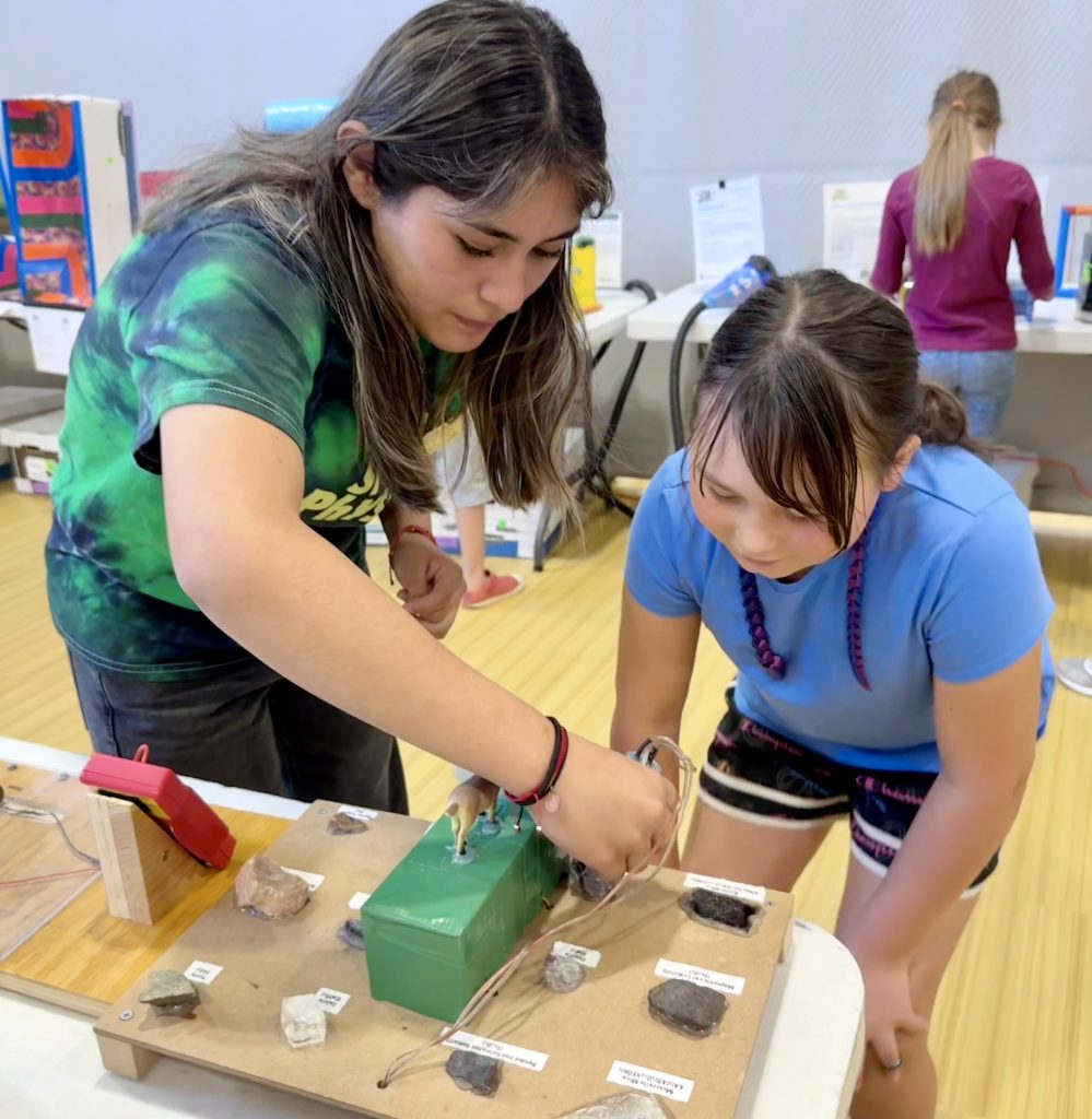 54829123201_fdc2bf8786_k Intern in tie dye holding probe and touching rock as student looks on