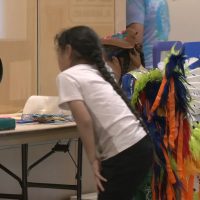 Two children, one in Native dress, look at LSOP experiments