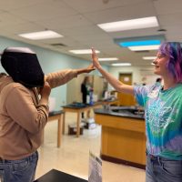 Spartan student wearing a helmet giving a high five to a LSOP intern wearing tie dye